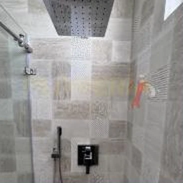 Ducha tipo rain shower instalada en un baño con azulejo gris